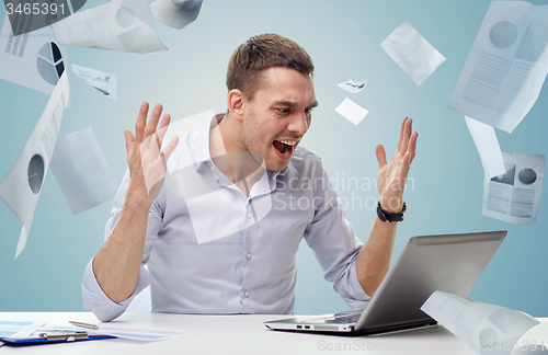 Image of angry businessman with laptop and papers shouting