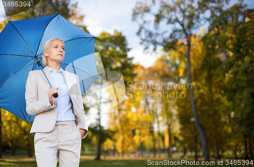 Image of businesswoman with umbrella over autumn background