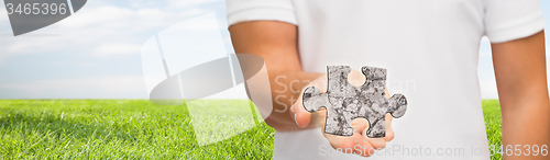 Image of man holding puzzle over natural background