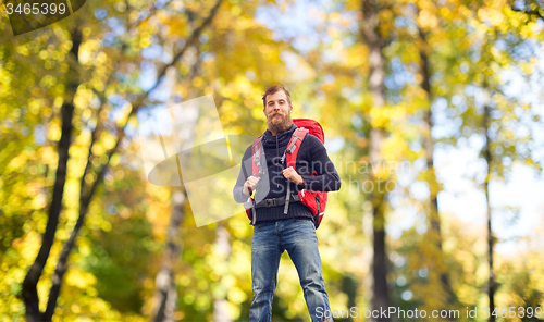 Image of tourist with beard and backpack raising hands