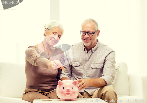 Image of senior couple with money and piggy bank at home