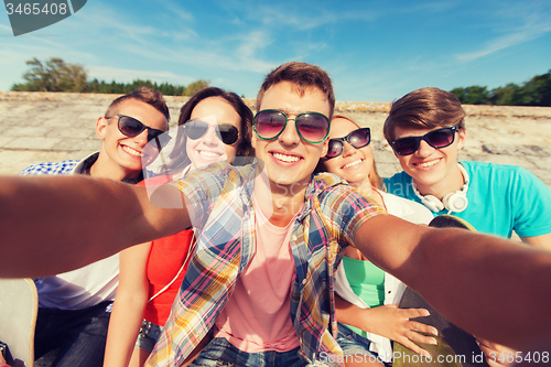 Image of group of smiling friends making selfie outdoors