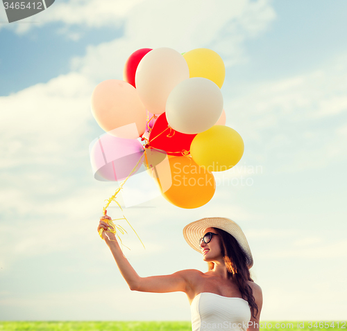 Image of smiling young woman in sunglasses with balloons