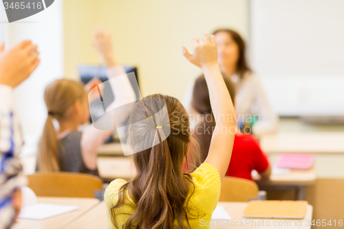 Image of group of school kids raising hands in classroom