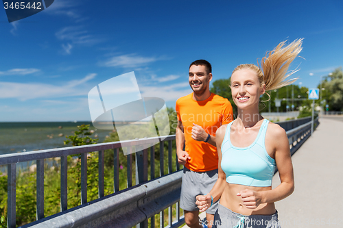 Image of smiling couple running at summer seaside