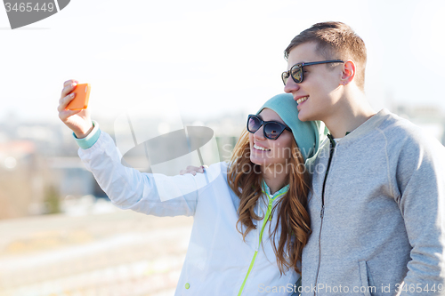 Image of smiling couple with smartphone taking selfie