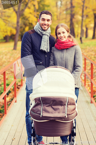 Image of smiling couple with baby pram in autumn park