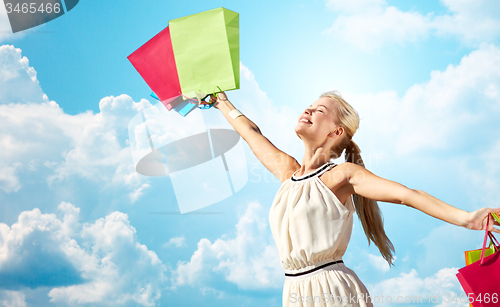 Image of smiling woman with shopping bag rising hands