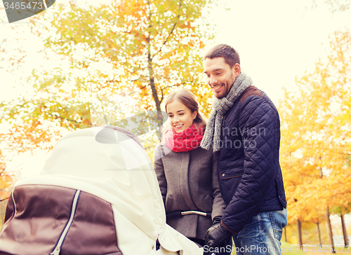 Image of smiling couple with baby pram in autumn park