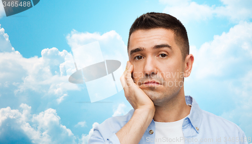 Image of bored man face over blue sky and clouds background