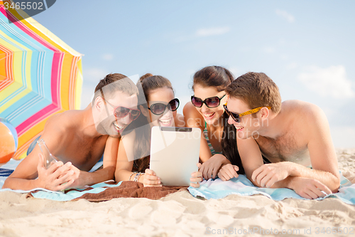 Image of happy friends with tablet pc on beach