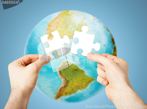 Image of hands with white blank puzzle over earth globe