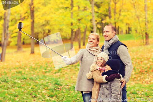 Image of happy family with smartphone and monopod in park