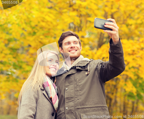 Image of smiling couple hugging in autumn park