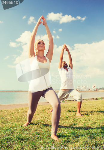 Image of couple making yoga exercises outdoors