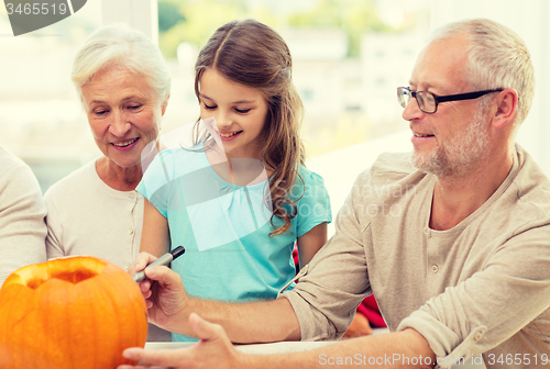 Image of happy family sitting with pumpkins at home