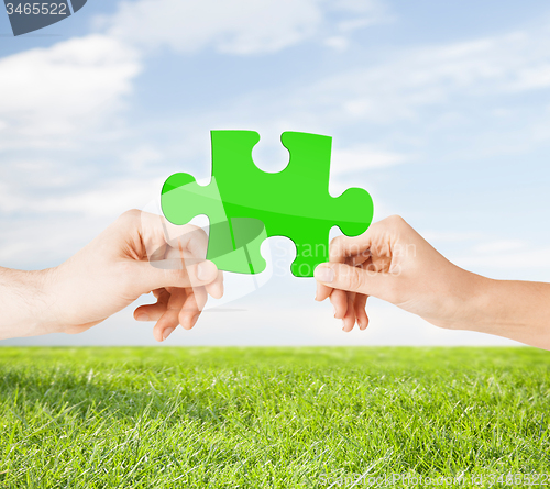 Image of hands with green puzzle over natural background