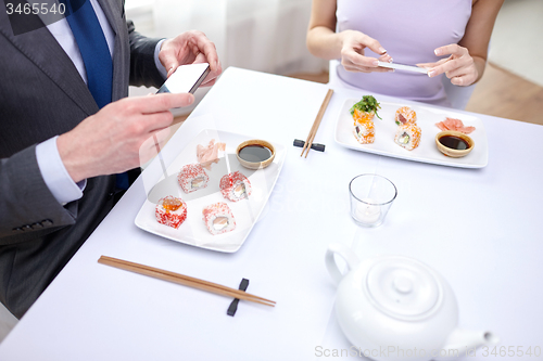 Image of close up of couple with smartphones at restaurant