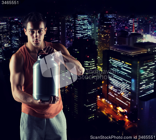 Image of young male bodybuilder holding jar with protein