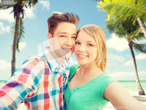 Image of smiling couple with smartphone on summer beach