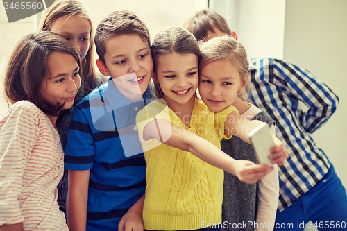 Image of group of school kids taking selfie with smartphone