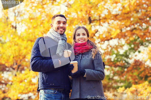 Image of smiling couple with coffee cups in autumn park