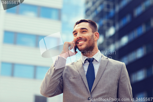 Image of smiling businessman with smartphone outdoors