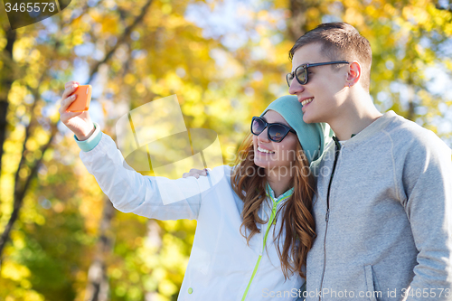 Image of smiling couple with smartphone taking selfie