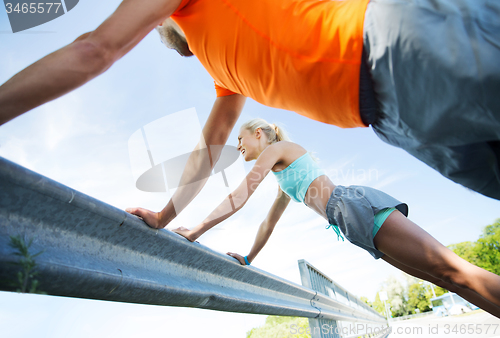 Image of close up of happy couple doing push-ups outdoors