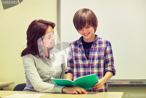 Image of school boy with notebook and teacher in classroom