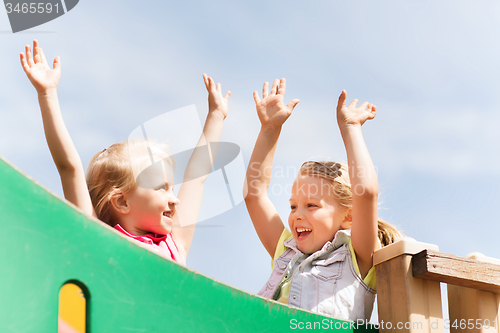 Image of happy girls waving hands on children playground