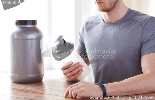 Image of close up of man with protein shake bottle and jar