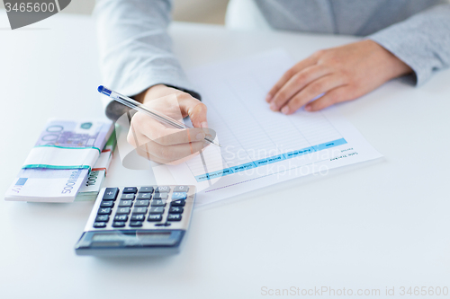 Image of close up of hands counting money with calculator