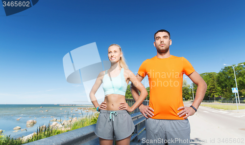 Image of happy couple exercising at summer seaside