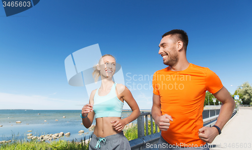 Image of smiling couple running at summer seaside