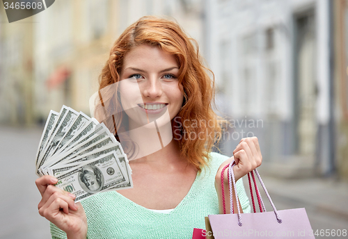 Image of happy woman with shopping bags and money on street