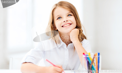 Image of smiling little student girl drawing at school