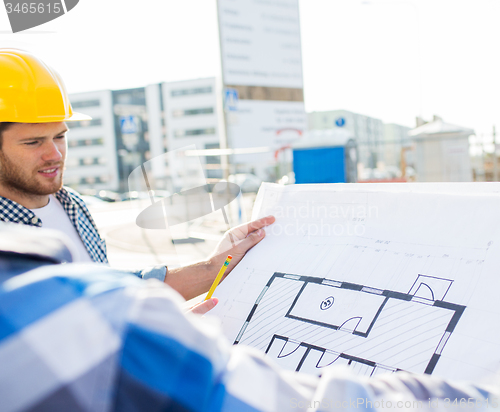 Image of close up of builders with blueprint at building