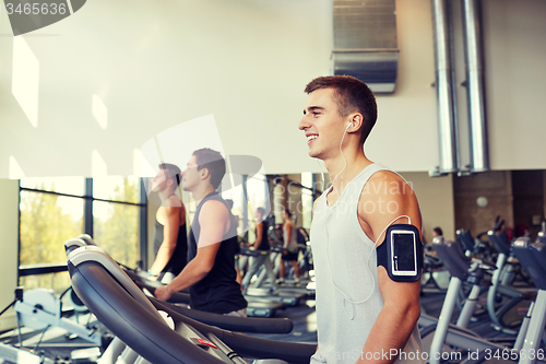 Image of man with smartphone exercising on treadmill in gym