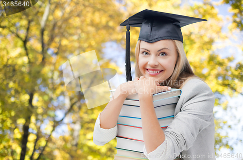 Image of happy student girl in bachelor cap with books