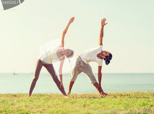 Image of couple making yoga exercises outdoors