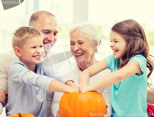 Image of happy family sitting with pumpkins at home