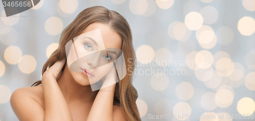 Image of beautiful young woman face over holidays lights