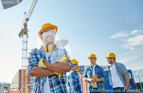 Image of group of smiling builders in hardhats outdoors