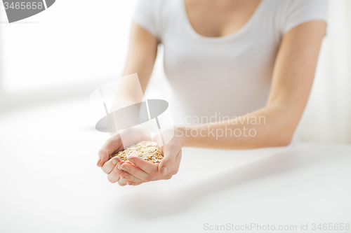 Image of close up of woman hands holding oatmeal flakes