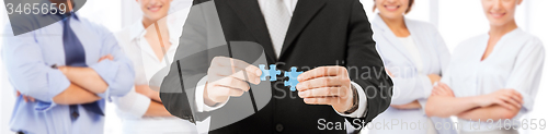 Image of man matching puzzle pieces over business team