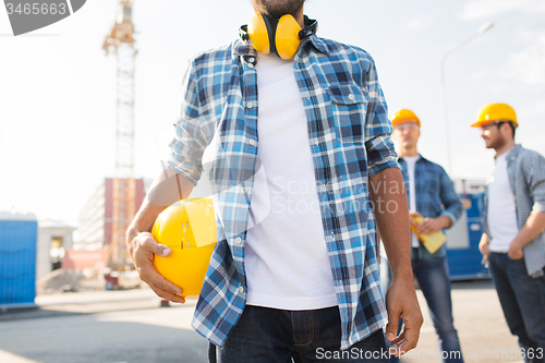 Image of close up of builder holding hardhat at building