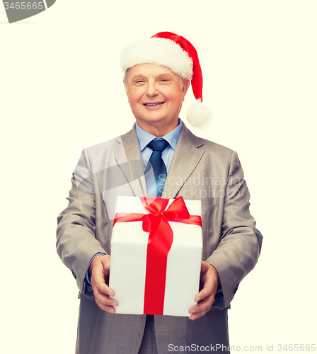 Image of smiling man in suit and santa helper hat with gift