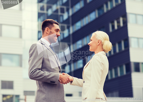 Image of smiling businessmen standing over office building