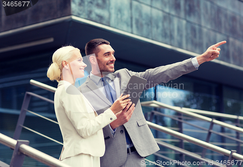 Image of smiling businessmen with tablet pc outdoors